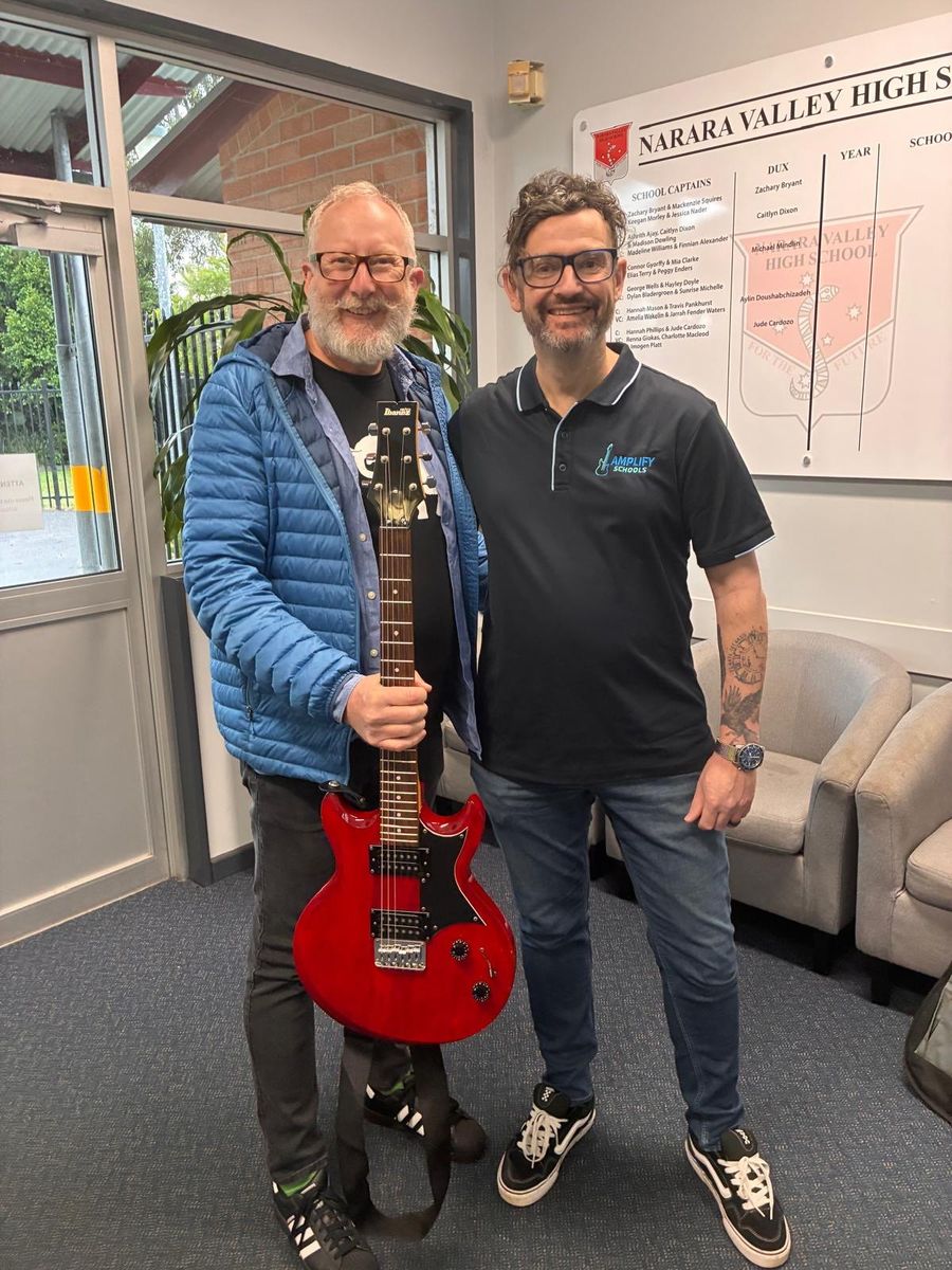 Handing over a refurbished red electric guitar at Narara Valley High School
